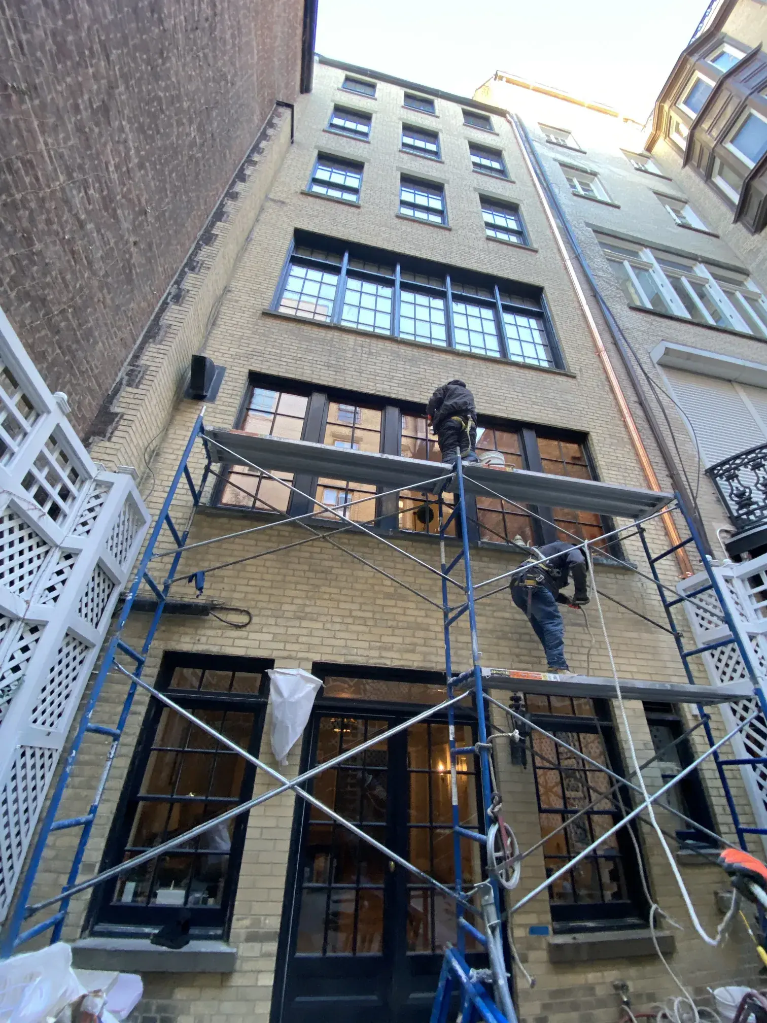 Scaffolded NYC townhouse facade with crew working on the exterior wall