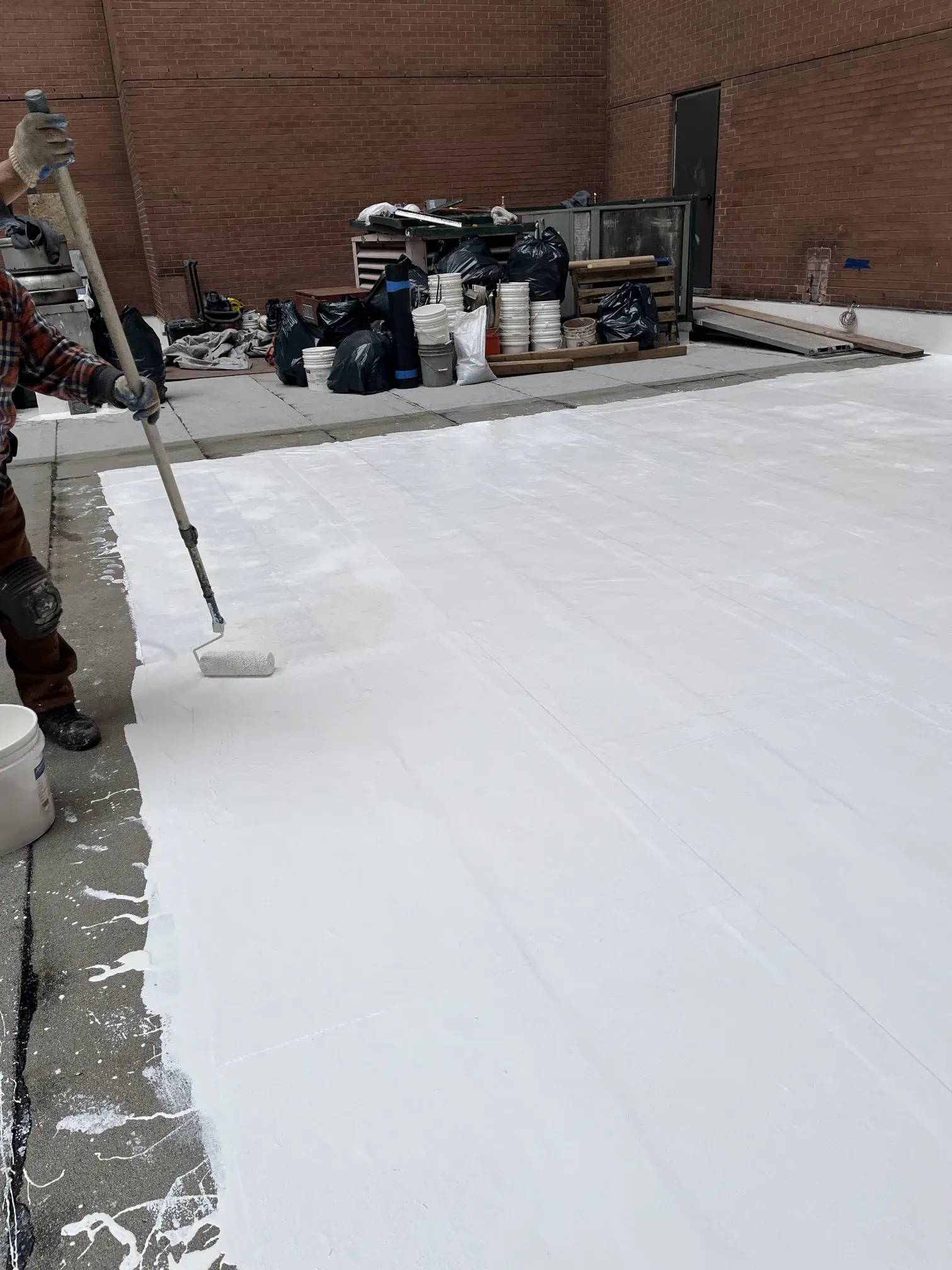 LANY crew rolling a liquid-applied PMMA membrane onto an NYC roof deck